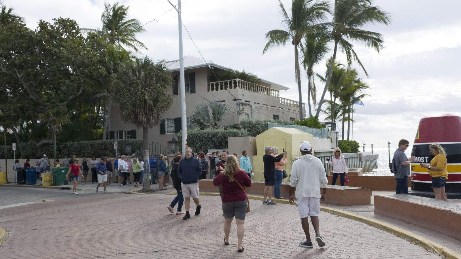 Visitors walking toward the Southernmost Point area in Key West under palm trees