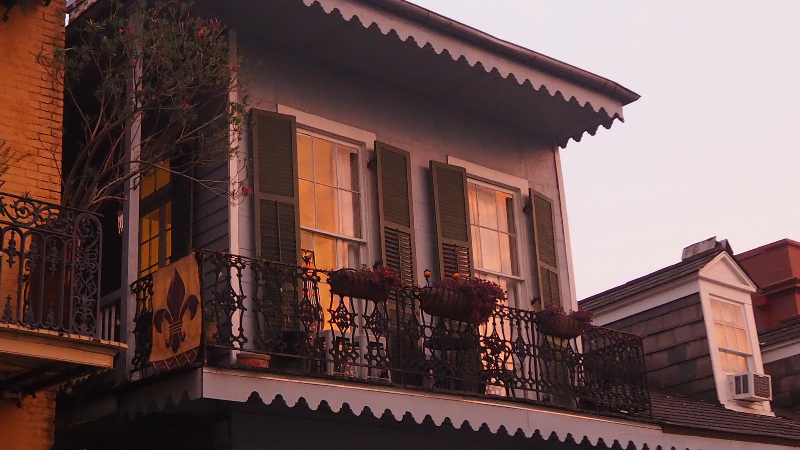 A French Quarter townhouse with an iron-lace balcony and dormer windows at dusk