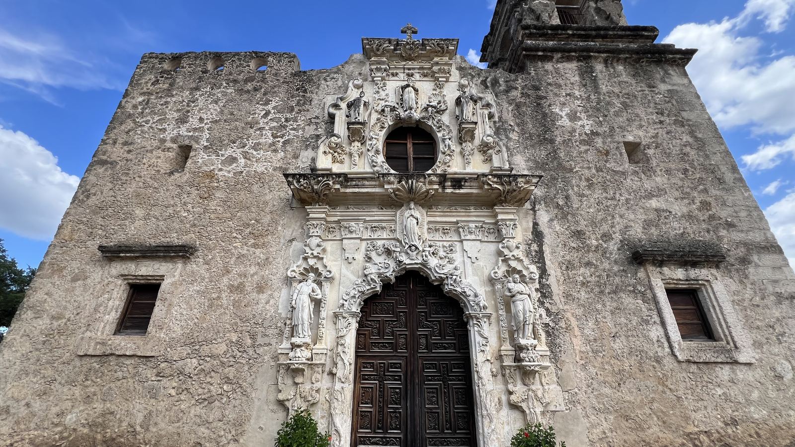 The carved stone entrance and bell tower of Mission San José in San Antonio